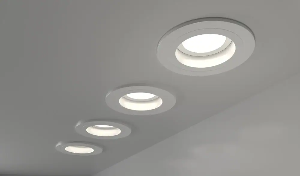 Four recessed ceiling lights are installed in a row on a smooth, white ceiling, professionally fitted by an electrician in Cook and Will County, IL, to create a modern and evenly lit appearance.