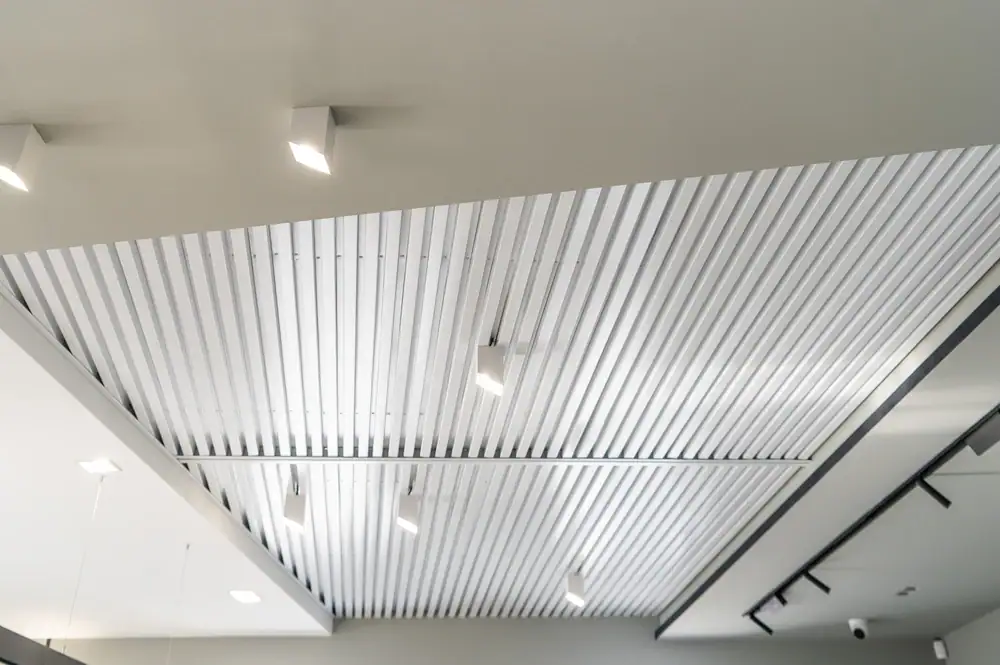 Modern ceiling with parallel metallic slats and recessed square LED lights, designed by an IL electrician. The evenly spaced lights create a sleek, contemporary look, perfect for homes or businesses in Cook and Will County seeking expert electrical services.