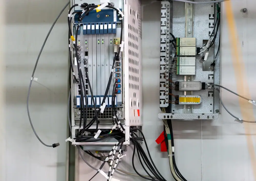 An open electrical cabinet displaying organized cables, wires, circuit boards, and relays connected to panels inside—some labeled for identification by an electrician Cook and Will County.
