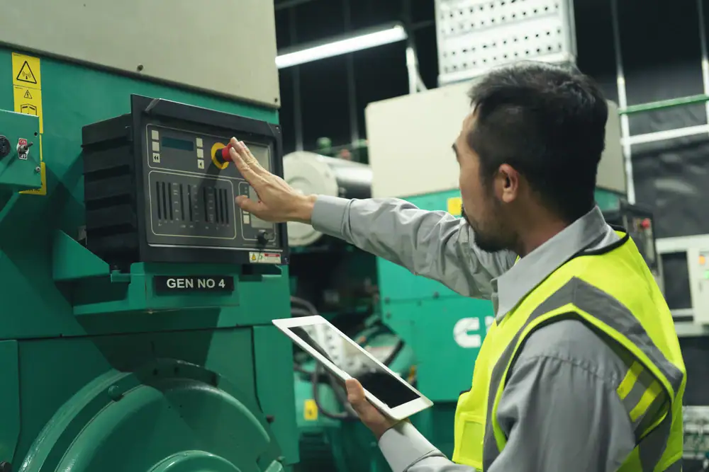 A man wearing a high-visibility vest operates control panels on industrial equipment, pressing a button with one hand while holding a tablet device in the other—exemplifying top-tier Electrical Services Cook and Will County, IL.