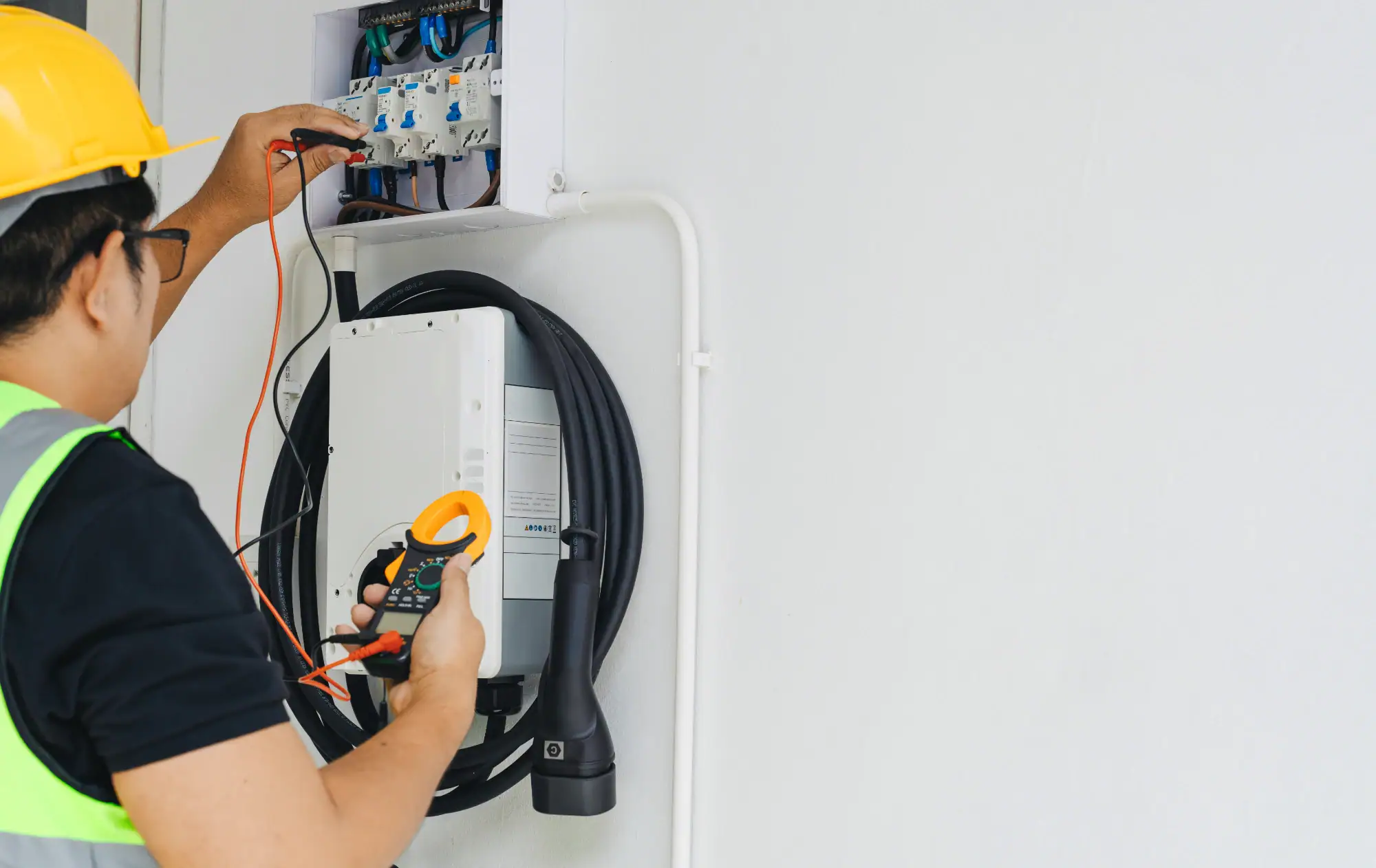 An electrician working on wiring in a residential home in Cook & Will County, IL. The electrician is wearing safety gear, including gloves and a helmet, while handling electrical components inside a circuit panel.