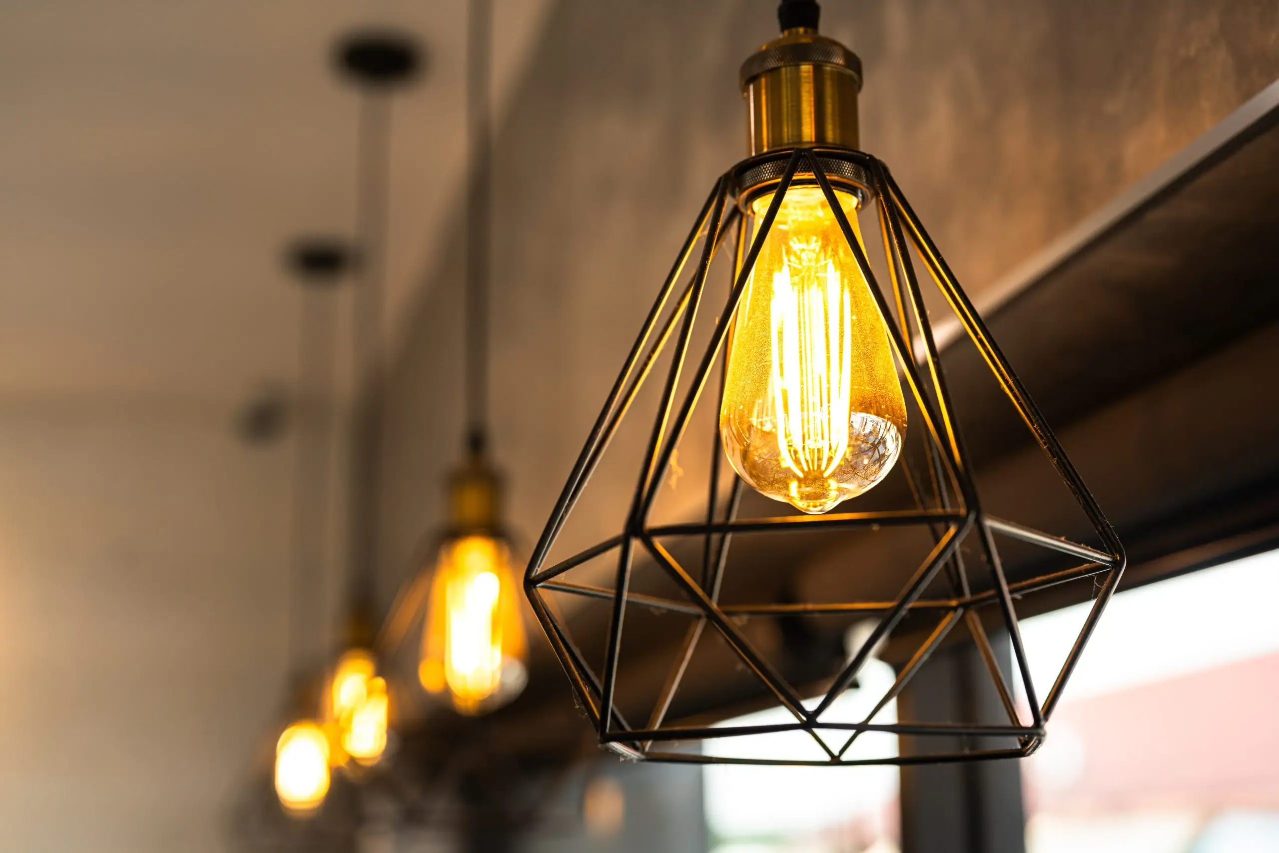Industrial lighting fixture hanging from the ceiling, providing bright illumination in a warehouse or factory setting in Cook & Will County, IL. The fixture features a robust metal design with multiple bulbs, casting a focused light on the workspace below.