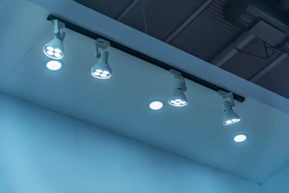 Ceiling track lighting with four adjustable LED spotlights and three recessed lights, all illuminated, in a modern indoor setting with a blue-toned ambiance—ideal for showcasing the expertise of an electrician Cook and Will County, IL.