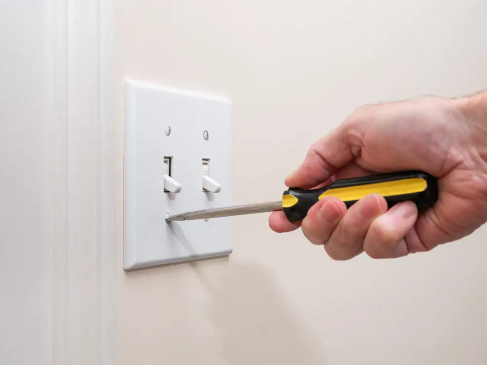 An electrician installing a new light switch in a home in Cook and Will County, IL. The image shows the electrician carefully screwing into the wall, ensuring a secure and functional installation.