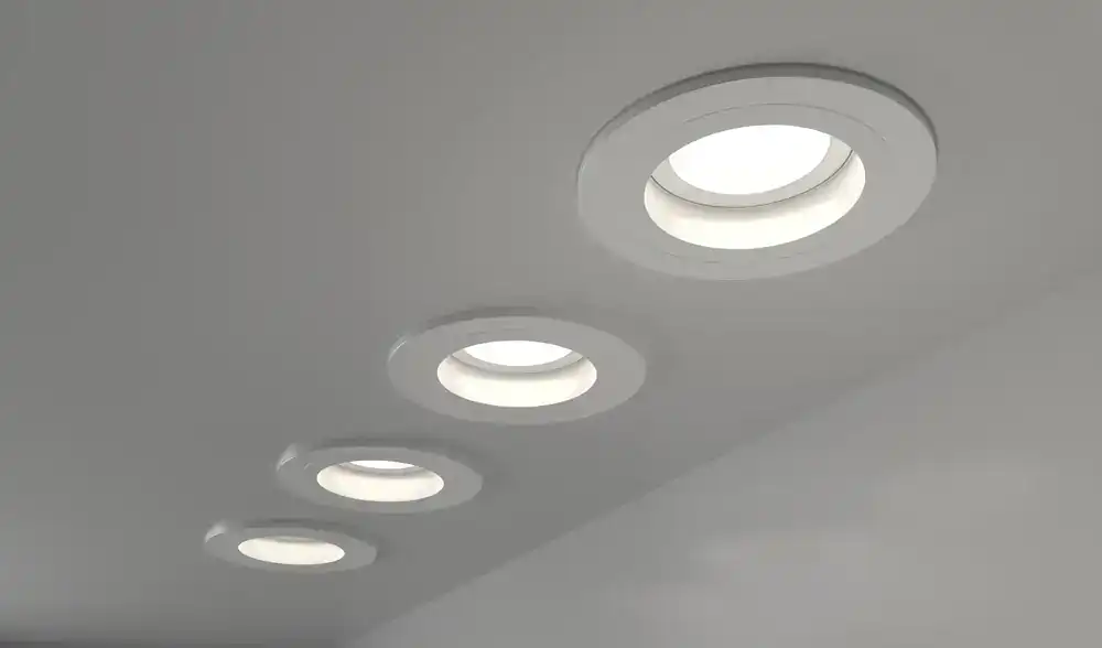 Four round recessed ceiling lights are evenly spaced on a smooth, light-colored ceiling, illuminating the area with a soft white glow.